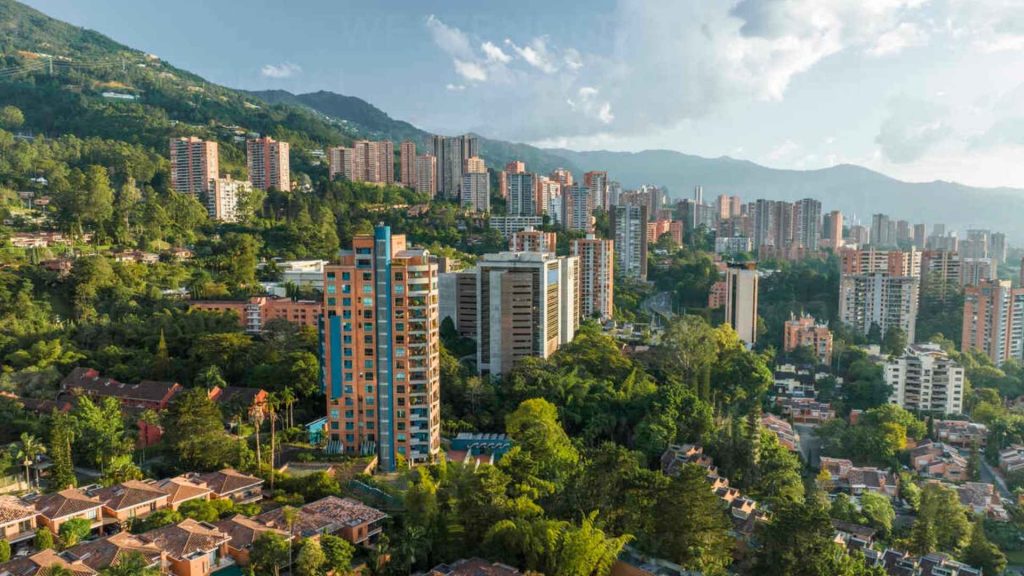 Vista panorámica de Medellín con edificios modernos y zonas verdes, representando el entorno urbano ideal para el trabajo remoto de lujo