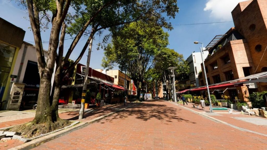 Calle peatonal de la Zona Rosa en Bogotá con restaurantes de lujo, toldos rojos y arquitectura de ladrillo en Rosales