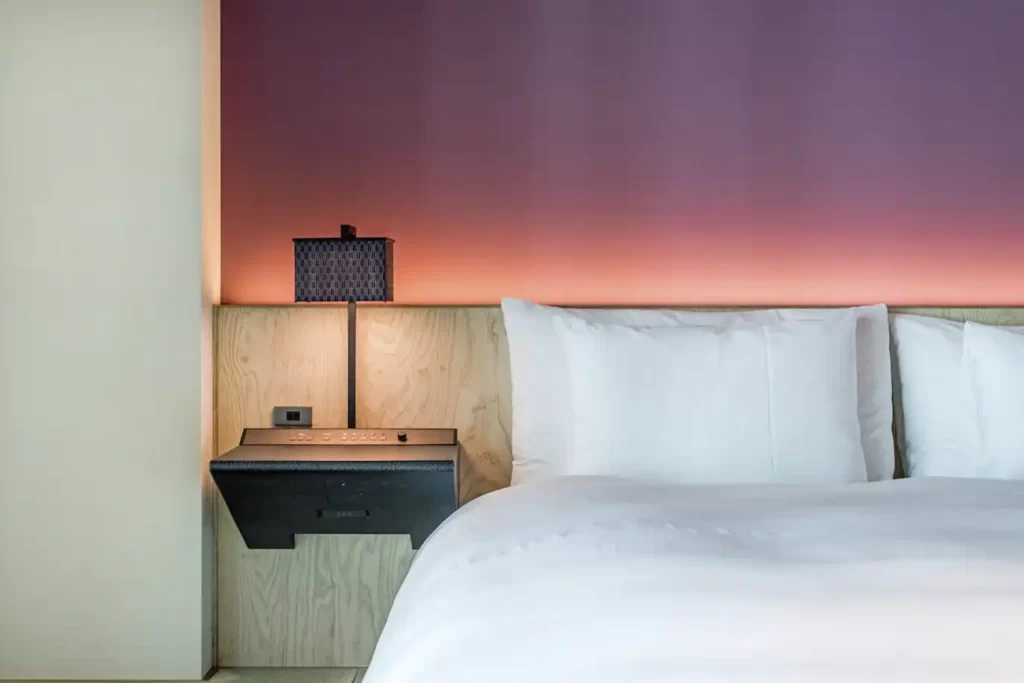 Dormitorio de diseño moderno en apartamento de lujo en Bogotá con iluminación de ambiente cálida y detalles de madera clara.