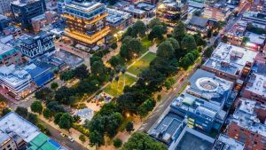 A nighttime aerial view of Parque de la 93 in Bogotá, surrounded by upscale restaurants and illuminated corporate buildings.
