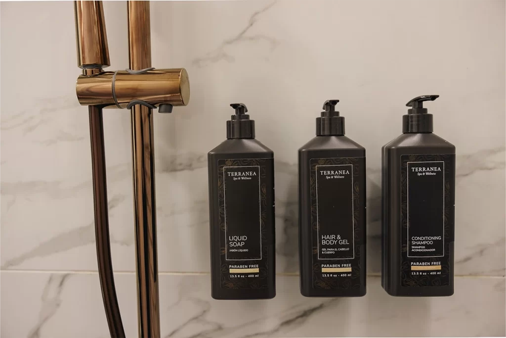 Amenities de baño sobre mármol blanco con grifería dorada en residencia de Bogotá.