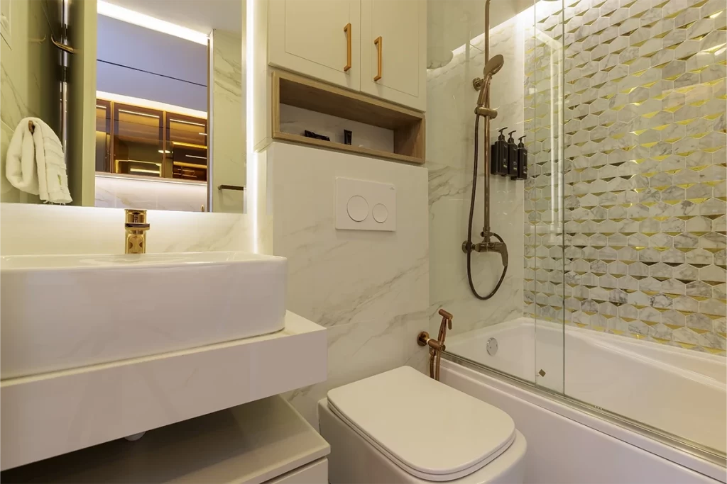 Baño de residencia con mármol blanco, grifería dorada y mosaico hexagonal en Bogotá.