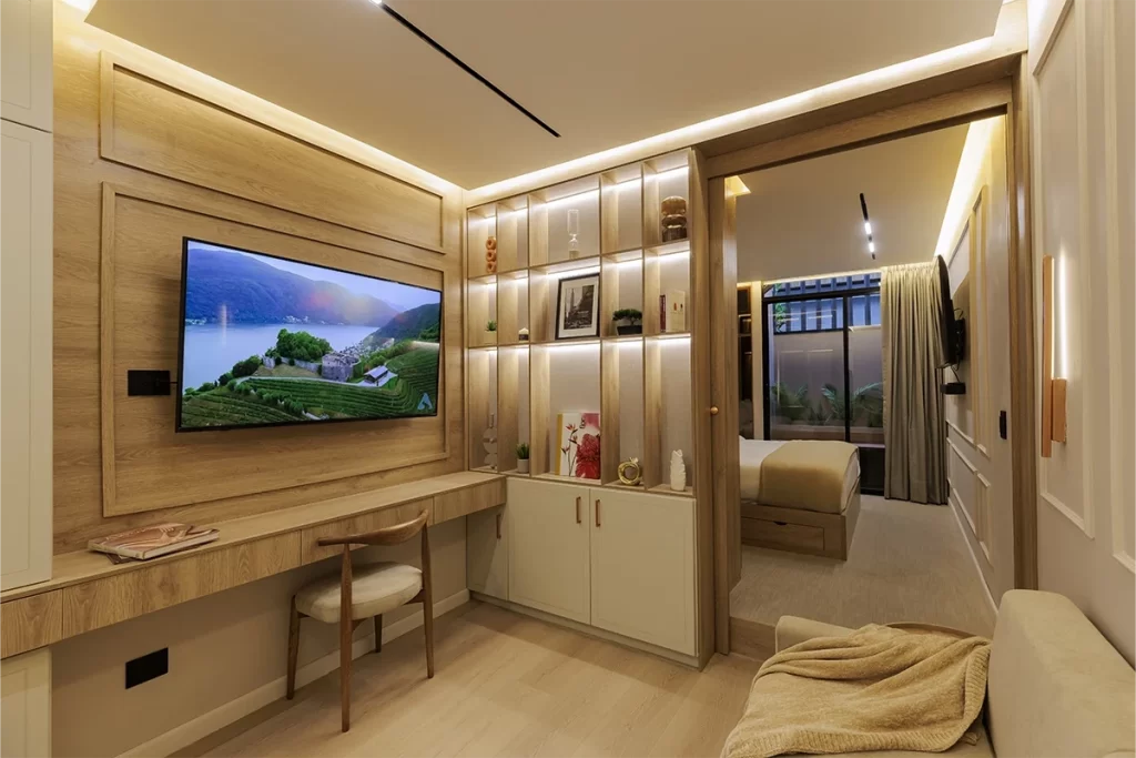 Sala de residencia con escritorio de madera, televisor y estantería iluminada en Bogotá.