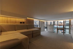 Sala de residencia con sofá modular, panel de madera iluminado y vista a Bogotá.