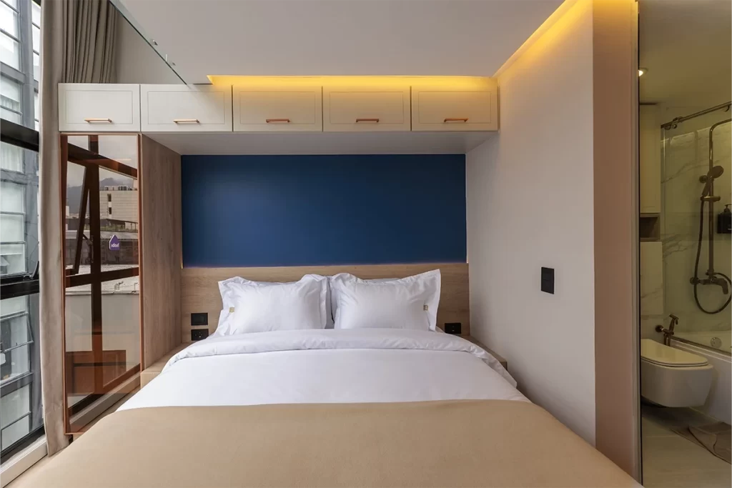 Dormitorio de loft con cama doble, cabecero azul y almacenamiento integrado en Bogotá.