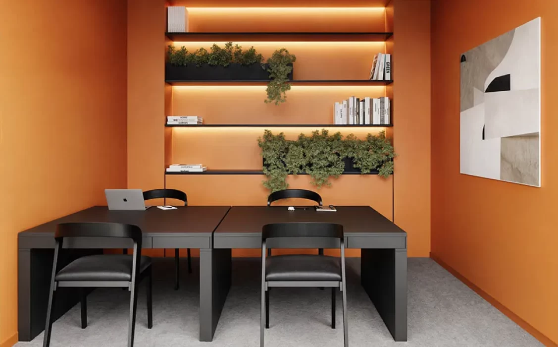 Zona de coworking en apartamento VEZRA Bogotá con mesa de trabajo negra, sillas y estantes con plantas
